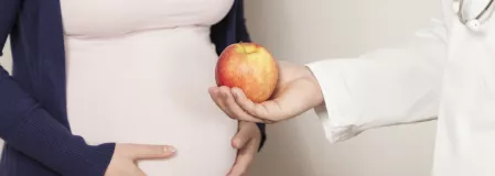 Schwangere mit Arzt und Apfel
