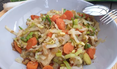 Winter-Gemüsepfanne auf einem Teller angerichtet. Die Pfanne besteht aus Weißkohl, Zwiebel, Karotten und Lauch