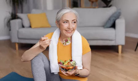 Ältere sportliche Frau isst Salat