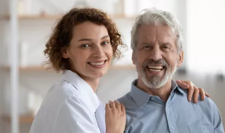 Eine Frau und ein älterer Mann lächeln in die Kamera