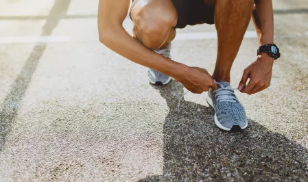 Mann beim Laufen/Schuhe binden