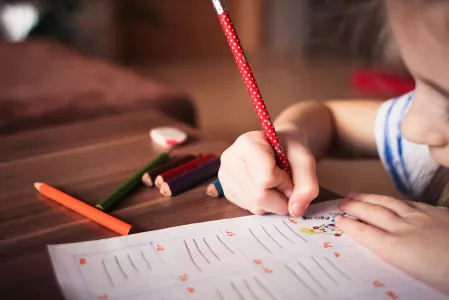 Schule: Kind schreibt mit Stiften Schule: Kind schreibt mit Stiften