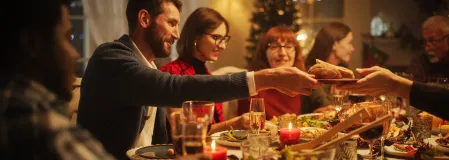 mehrere Menschen essen an einem feierlich gedeckten Tisch