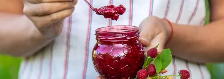 Ein Glas Himbeermarmelade und frische Himbeeren