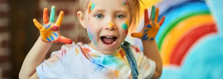 M&auml;dchen in der Nahaufnahme mit Farben bemalt und Pinsel im Haar