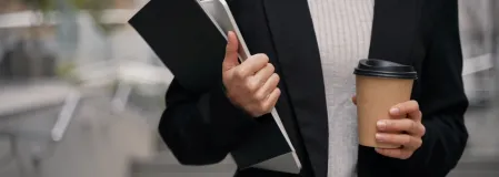 Eine Gesch&auml;ftsfrau unterwegs mit Laptop, Folder und Coffee to go