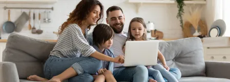 Familie sitzt vor einem Laptop