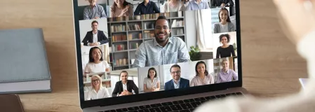 Person vor einem Laptopbildschirm, auf dem viele einzelne Menschen im Portrait zu sehen sind