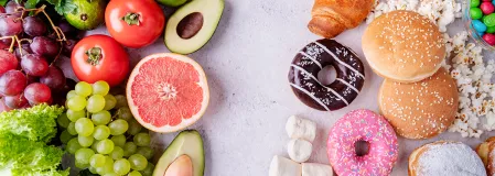 versteckter Zucker Das Bild ist in zwei Teile geteilt: Links liegt frisches Obst und Gemüse. Rechts liegen Mehlspeisen wie Donuts, Croissants und Berliner, Hamburgerbrötchen sowie Süßigkeiten.