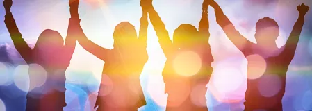Vier Personen, die etwas feiern, Aufnahme mit unscharfem Hintergrund und Gegenlicht Vier Personen, die etwas feiern, Aufnahme mit unscharfem Hintergrund und Gegenlicht