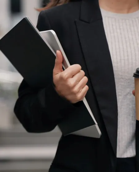 Eine Gesch&auml;ftsfrau unterwegs mit Laptop, Folder und Coffee to go