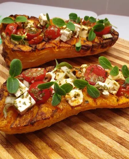 gefüllter Butternut-Kürbis Zwei halbierte Butternut Kürbisse sind mit Feta und Tomaten gefüllt.