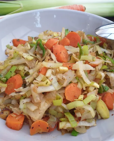 Winter-Gemüsepfanne Winter-Gemüsepfanne auf einem Teller angerichtet. Die Pfanne besteht aus Weißkohl, Zwiebel, Karotten und Lauch