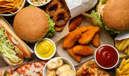 Hoch verarbeitete Lebensmittel Unterschiedliche hoch verarbeitete Lebensmittel: Burger, Pizza, Nuggets, Zwiebelringe, Pommes etc.