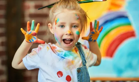 Mädchen in der Nahaufnahme mit Farben bemalt und Pinsel im Haar