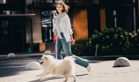 Eine Frau geht mit ihrem Hund spazieren. Sie rennen.