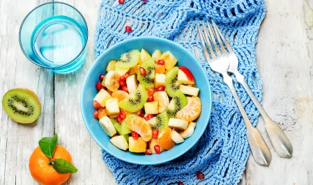 Winter-Obst In einer blauen Schale ist Obstsalat mit folgendem Obst angerichtet: Apfel, Kiwi, Banane, Mandarine, Granatapfel,