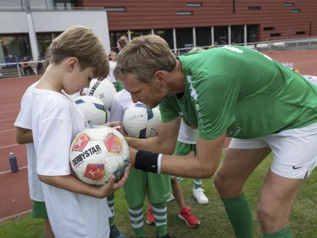 FC Diabetologie vs. FC Bundestag 2025: ein Spieler des FC Diabetologie unterschreibt das Trikot eines Jungen