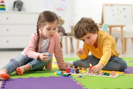 Junge und M&auml;dchen spielen zusammen auf dem Boden