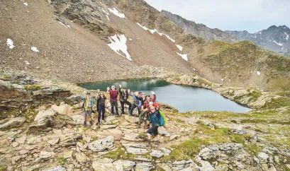 Eine Drohnenaufnahme von der Gruppe vor einem kleinen Bergsee