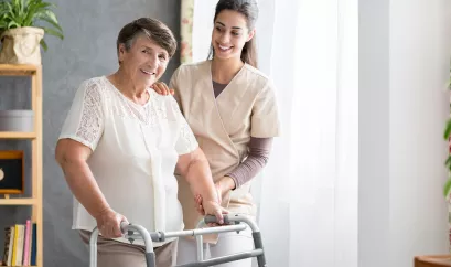 Ältere Frau mit Rollator und junge Pflegekraft