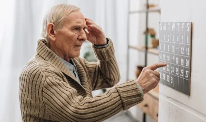 ein &auml;lterer Mann schaut verwirrt auf einen Wandkalender