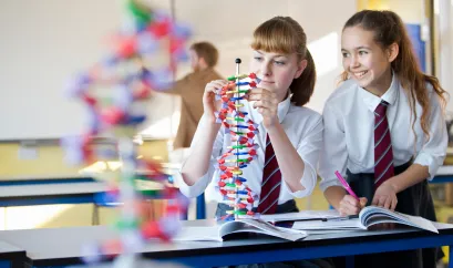 Zwei M&auml;dchen in Schuluniform im Chemieunterricht 