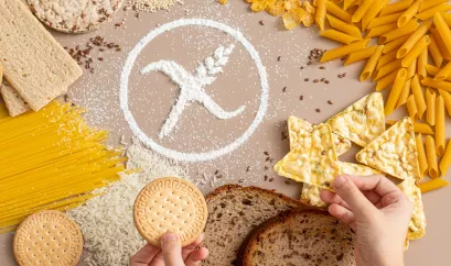 Glutenhaltige Lebensmittel wie Nudeln, Brot, Gebäck auf einem Tisch. In der Mitte ist aus mehr das "glutenfrei" Zeichen, ein durchgestrichenes Getreide, aus Mehl gelegt.