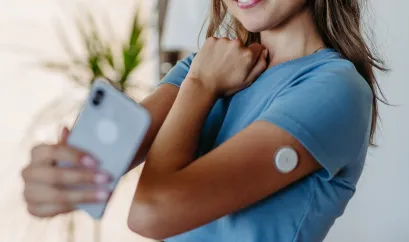 Eine junge Frau macht ein Selfie und hält ihren Sensor auf dem Arm in die Kamera in