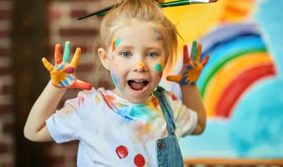 M&auml;dchen in der Nahaufnahme mit Farben bemalt und Pinsel im Haar