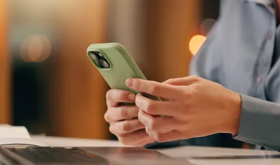 Frau mit Smartphone und Laptop beim Arbeiten