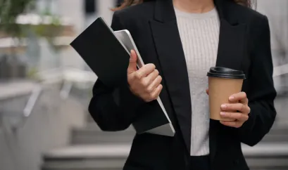 Eine Gesch&auml;ftsfrau unterwegs mit Laptop, Folder und Coffee to go