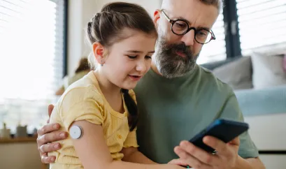 Mädchen mit Sensor auf dem Schoß von Vater 