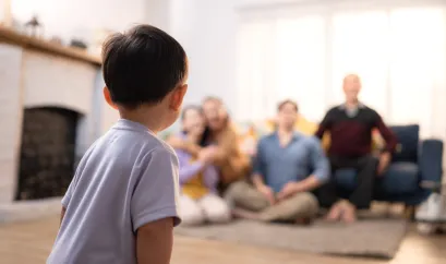 Ein Kind schaut auf seine Familie, die verschwommen im Hintergrund zu sehen ist.
