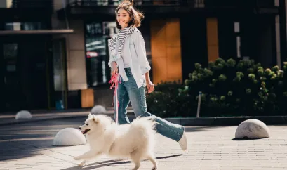 Eine Frau geht mit ihrem Hund spazieren. Sie rennen.