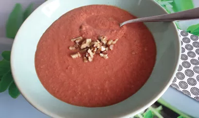 Die rote Gemüsesuppe ist in einer Schüssel angerichtet und mit gehackten Walnüssen garniert. 