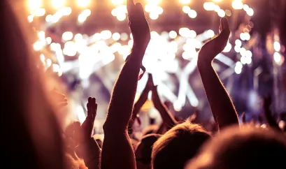 Eine Menschenmenge bei einem Konzert. Die Menschen halten die Hände nach oben und klatschen