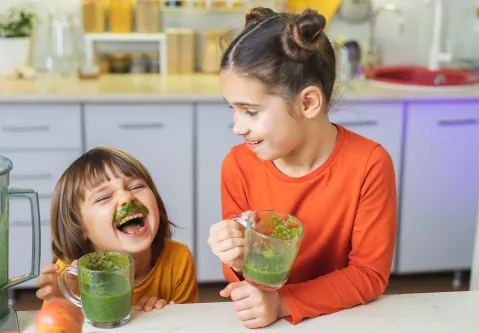 Ein Junge und Mädchen trinken grünen Smoothie