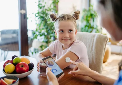 Mädchen mit Sensor am linken Arm mit Mutter 