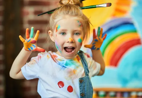 Kind mit Farbe im Gesicht und Pinsel im Haar
