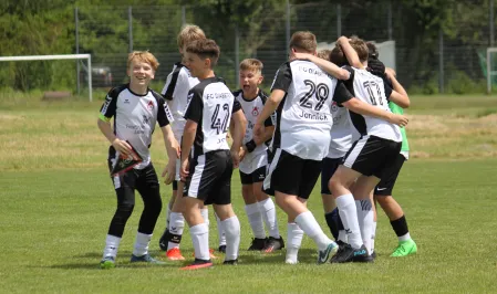 Das Fußballteam FC Diabetes feiert auf dem Fußballplatz. Sie tragen schwarz-weiße Trikots