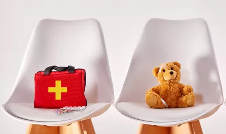 Stofftiere und Erste-Hilfe-Koffer auf einer Reihe von St&uuml;hlen