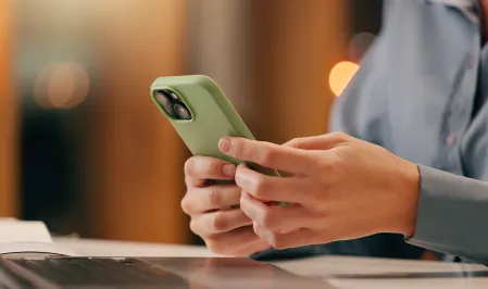 Frau mit Smartphone und Laptop beim Arbeiten