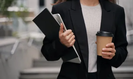 Eine Gesch&auml;ftsfrau unterwegs mit Laptop, Folder und Coffee to go