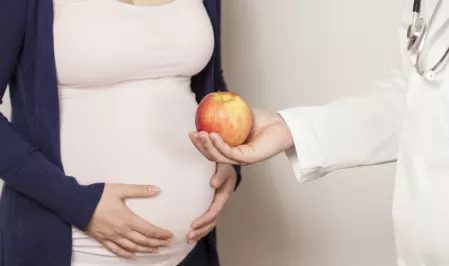 Schwangere mit Arzt und Apfel