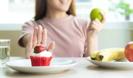 Frau isst Obst statt Muffin